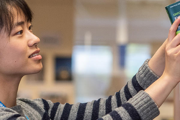 A student retrieves a book from a shelf